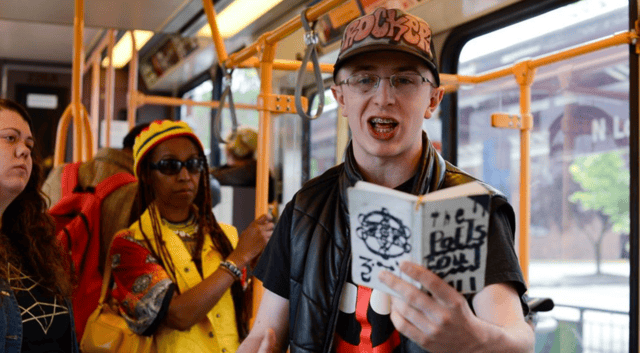 Photo of Micah holding a book of poetry inside of a bus.