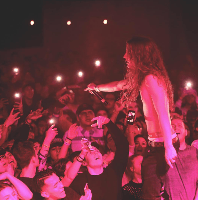 Photo of Yung Pinch performing live with fluorescent lights in the background.