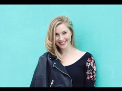 Photo of Tristin Hagen taken with the turquoise colored wall behind her.