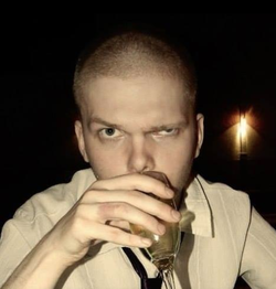 Photo of Vitaly Bespalov with buzzed hair drinking beer.