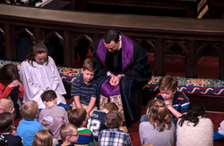 Photo of Andrew C. Stoker praying with children.