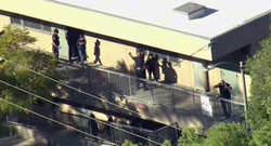 Photo of many of the students being escorted out of the classroom and to a place of safety from any other possible shooting in the area.