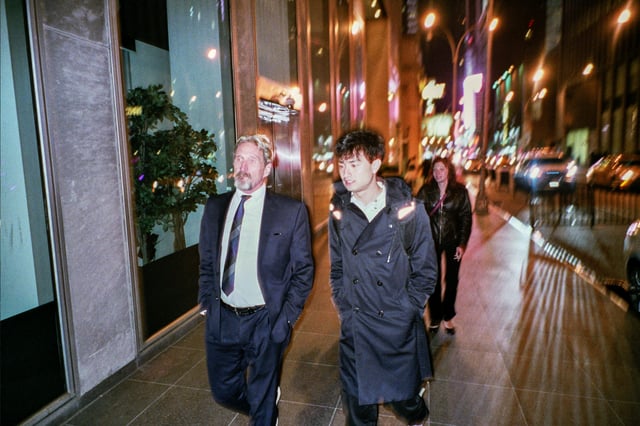 Zach walking with John McAfee while reporting a story.