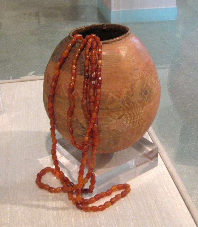 Harappan burnished and painted clay ovoid Vase, with round carnelian beads. (3rd Millennium-2nd Millennium BCE)