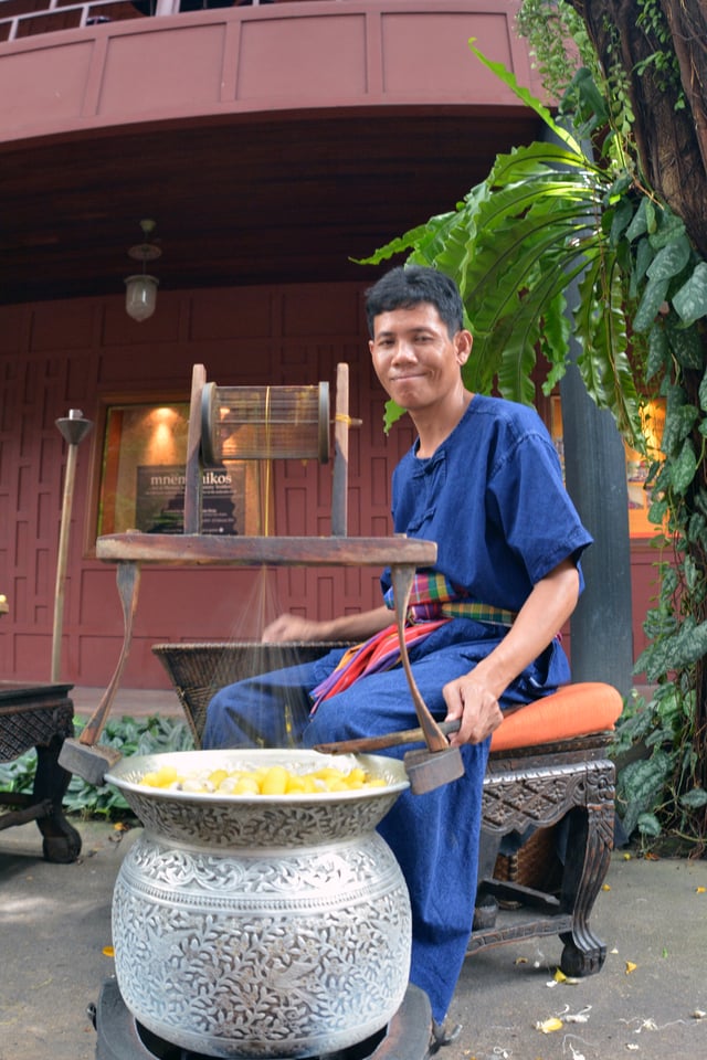 Thai man spools silk