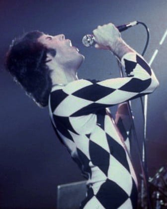Mercury performing in a Harlequin outfit. He appeared in a half black, half white version in the music video for “We Are the Champions”.