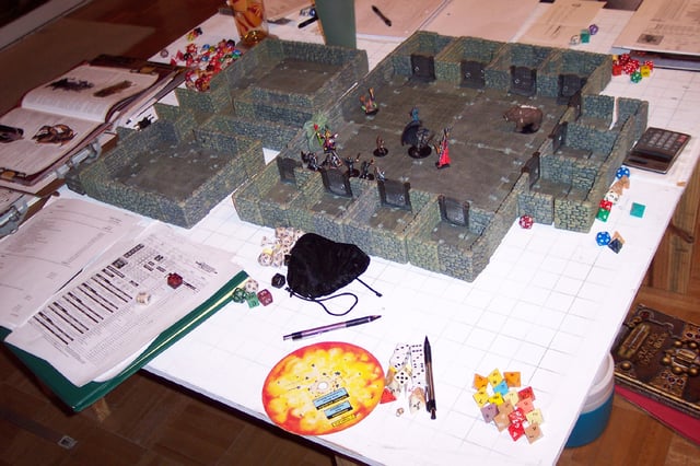 An elaborate D&D game in progress. Among the gaming aids here are dice, a variety of miniatures and a dungeon diorama.