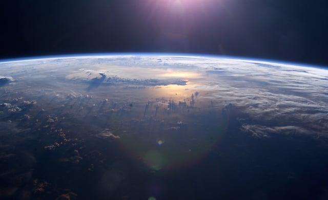 Sunset over the Pacific Ocean as seen from the International Space Station. Anvil tops of thunderclouds are also visible.