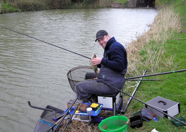 An angler on the Kennet and Avon Canal, England, with his tackle