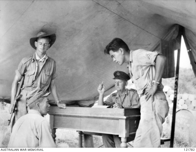 26 October 1945, Sandakan, North Borneo. During the investigation into Sandakan Death Marches and other incidents, Sergeant Hosotani Naoji (left, seated), a member of the Kempeitai unit at Sandakan, is interrogated by Squadron Leader F.G. Birchall (second right) of the Royal Australian Air Force, and Sergeant Mamo (right), a Nisei member of the U.S. Army/Allied Translator and Interpreter Service. Naoji confessed to shooting two Australian POWs and five ethnic Chinese civilians.