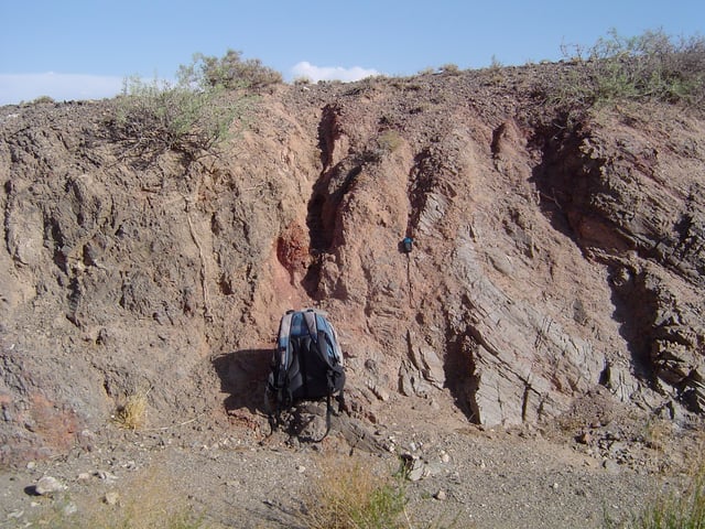 Salmon-colored fault gouge and associated fault separates two different rock types on the left (dark gray) and right (light gray). From the Gobi of Mongolia.