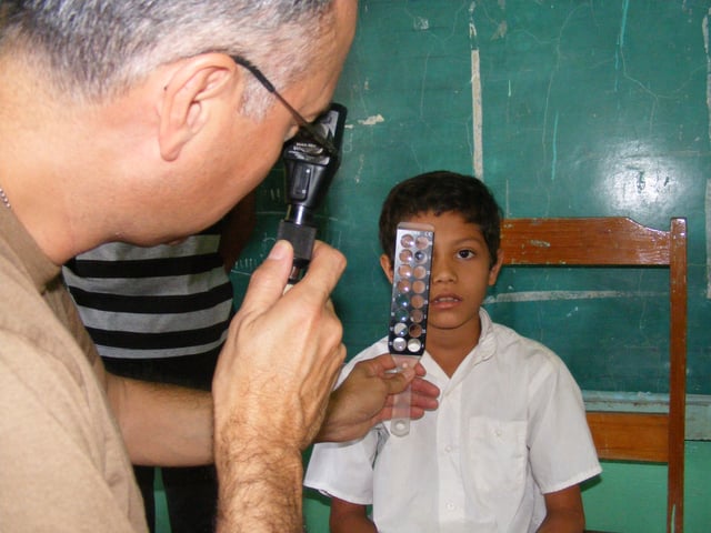 A U.S. Navy Reserve optometrist uses a retina scope and lens rack to check the eyes of 9-year-old Honduran boy during the Beyond the Horizon humanitarian assistance exercise in Honduras