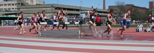 Men traversing the water jump in a steeplechase competition