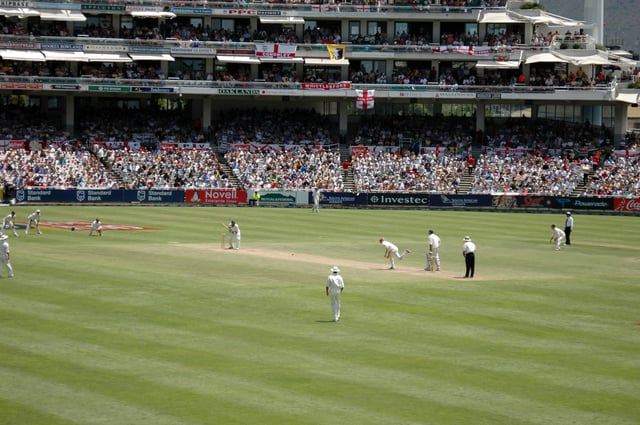 A Test match between South Africa and England in January 2005. The men wearing black trousers are the umpires. Teams in Test cricket, first-class cricket and club cricket wear traditional white uniforms and use red cricket balls.