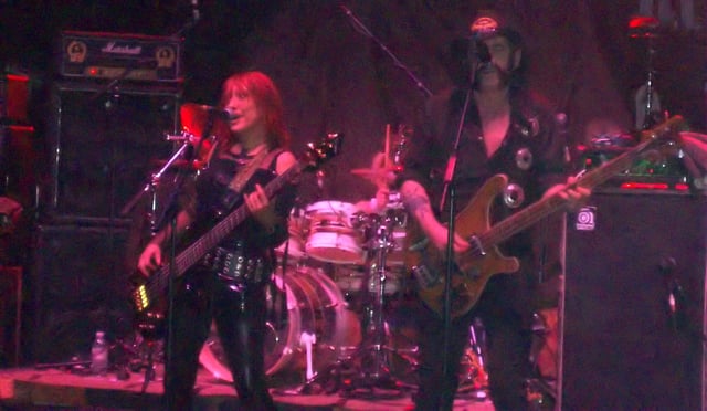 Enid Williams from Girlschool and Lemmy from Motörhead singing "Please Don't Touch" live in 2009. The ties that bind the two bands started in the 1980s and were still strong in the 2010s.