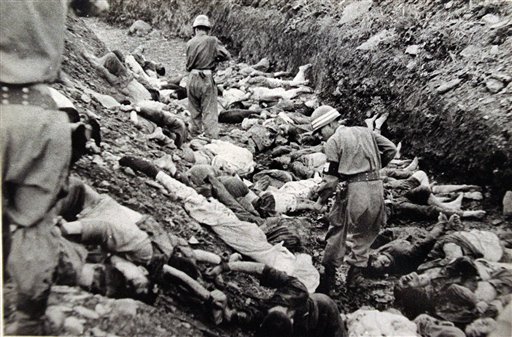 South Korean soldiers walk among the bodies of political prisoners executed near Daejon, July 1950