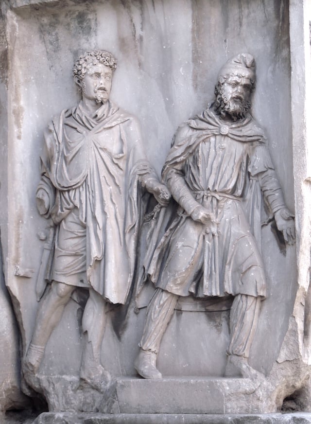 A Parthian (right) wearing a Phrygian cap, depicted as a prisoner of war in chains held by a Roman (left); Arch of Septimius Severus, Rome, 203 AD
