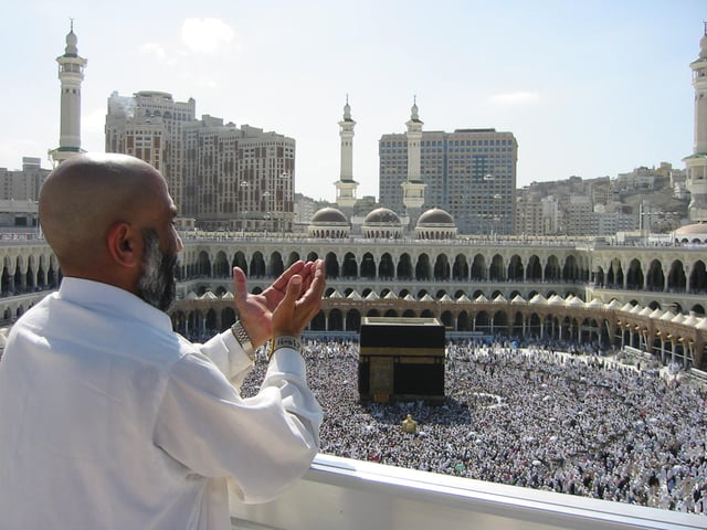 Supplicating pilgrim at Al-Masjid Al-Ḥarām (Arabic: ٱلْـمَـسْـجِـد ٱلْـحَـرَام‎, The Sacred Mosque) in Mecca. The Ka‘bah (Arabic: كَـعـبَـة‎, lit. 'Cube', Kaaba) is the cubic building in front of the pilgrim.