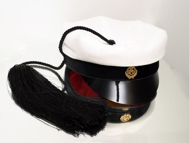 A traditional Finnish technology student's hat (teekkarilakki) photographed on top of a mirror.