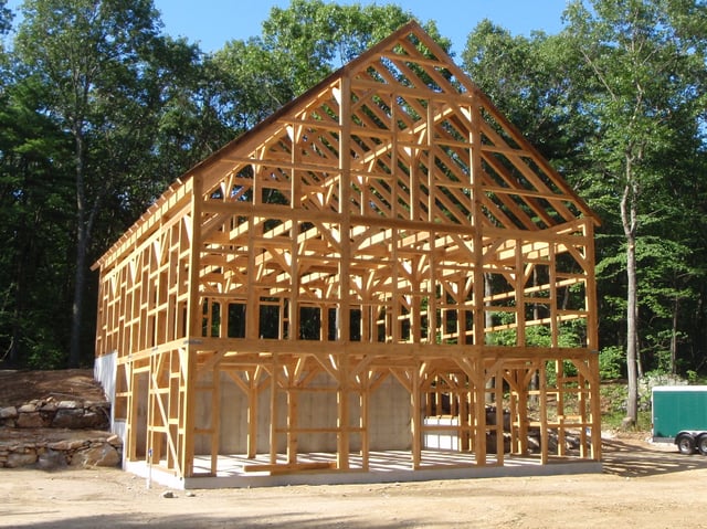 The skeleton of a post and beam horse barn just after raising