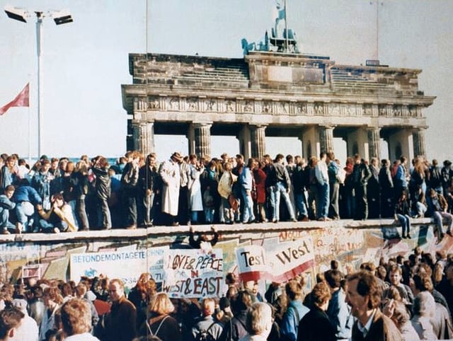 The Berlin Wall during its fall in 1989, with the Brandenburg Gate in the background.