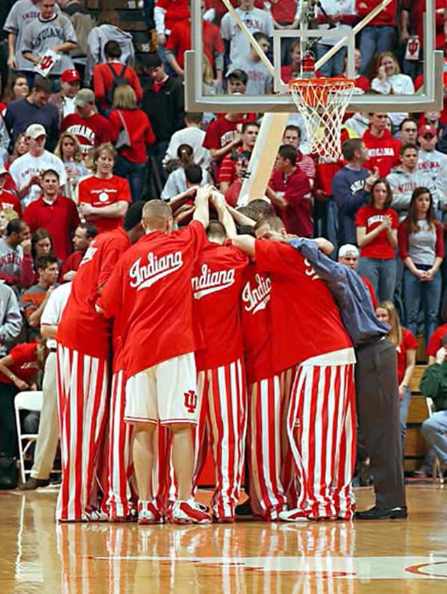 Basketball players huddle before a game in their candy striped pants.