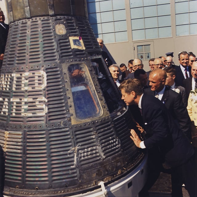 Accompanied by astronaut John Glenn, Kennedy inspects the Project Mercury capsule Friendship 7, 23 February 1962