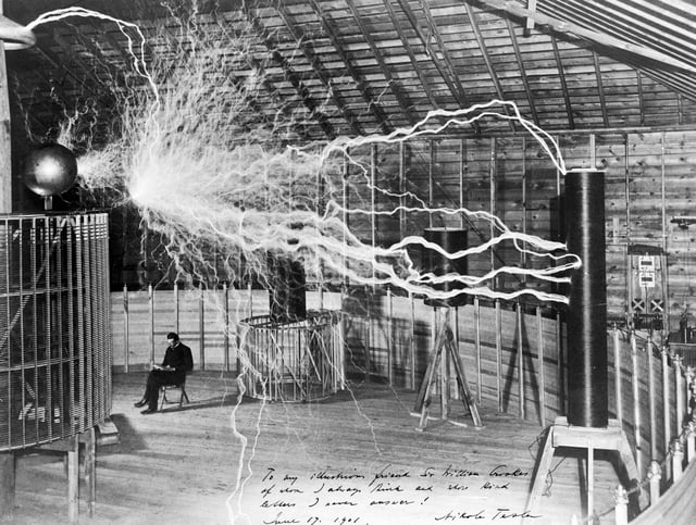 A multiple exposure picture of Tesla sitting next to his "magnifying transmitter" generating millions of volts. The 7-metre (23 ft) long arcs were not part of the normal operation, but only produced for effect by rapidly cycling the power switch.