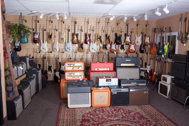A range of guitar combo amps and guitars for sale at a music store.