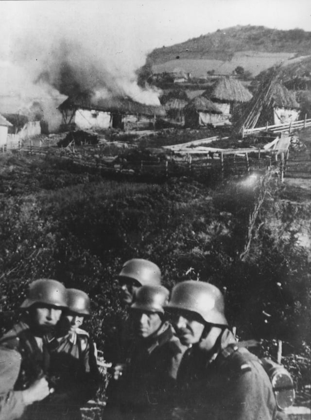 German soldiers set fire to a Serbian village near Mitrovica, circa 1941.