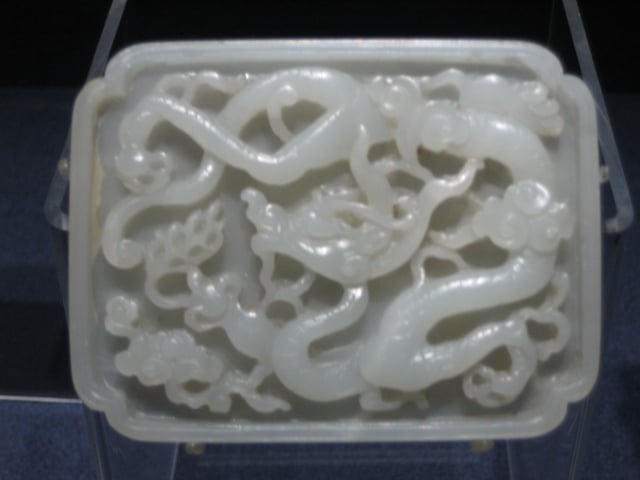 A Yuan dynasty jade belt plaque featuring carved designs of a dragon