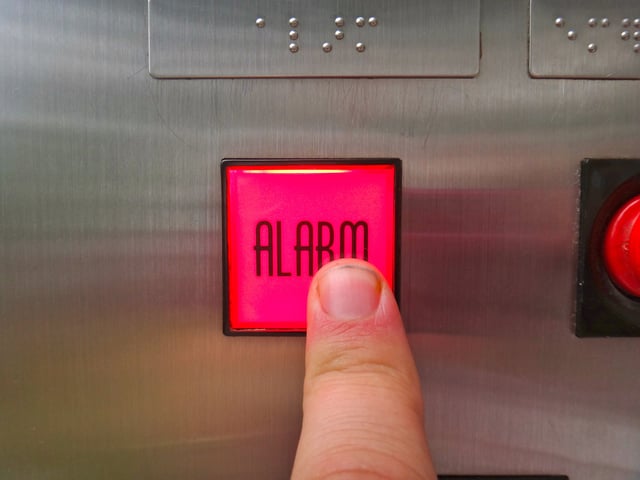 Using the emergency call button in an elevator.