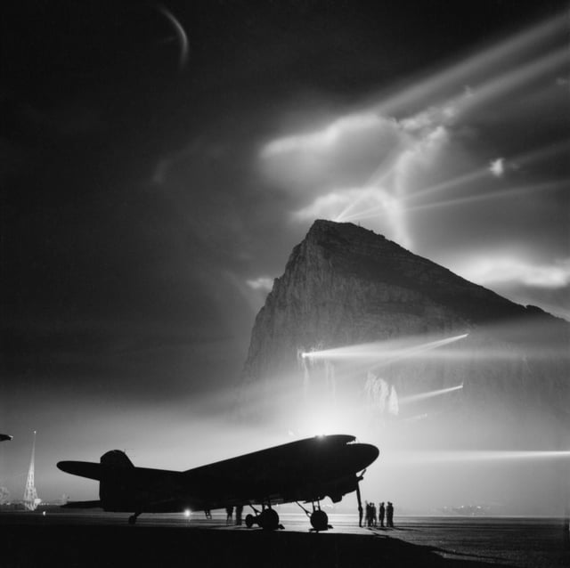 Shown here during the Second World War, a Douglas Dakota of BOAC is silhouetted at Gibraltar by the batteries of searchlights on the Rock, as crews prepare it for a night flight to the United Kingdom.