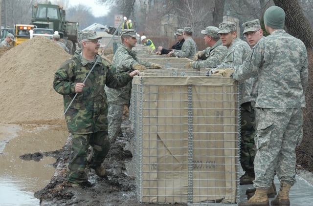 Soldiers assembling sections of a HESCO collapsible barrier device in Fargo, North Dakota
