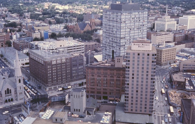 Downtown Denver cityscape, 1964. Includes Denver's oldest church (Trinity United Methodist), first building of the Mile High Center complex, Lincoln Center, old brownstone part of the Brown Palace Hotel, and Cosmopolitan Hotel – since demolished.
