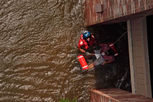 A Coast Guard Aviation Survival Technician assisting with the rescue of a pregnant woman during Hurricane Katrina in 2005.