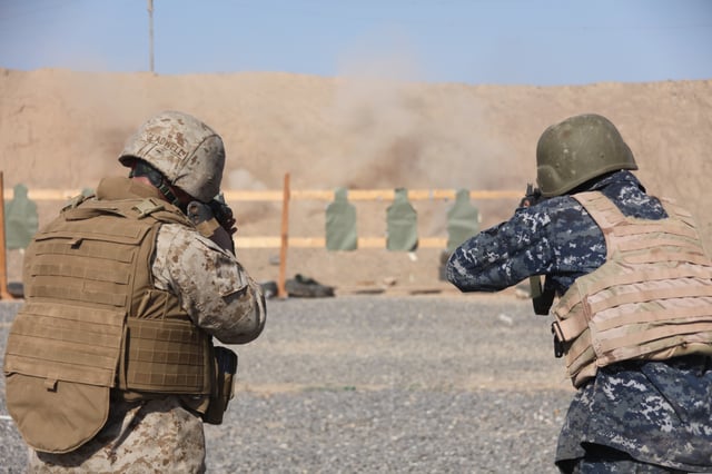 A Marine and sailor train with rifles in Iraq