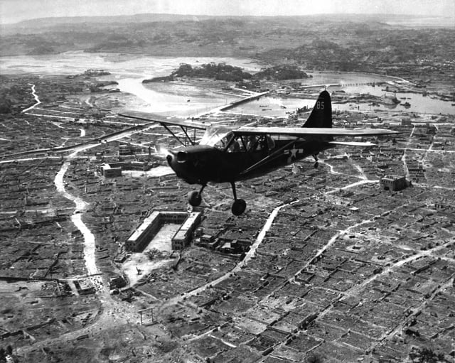 A US Marine Corps Stinson Sentinel observation plane flies over the razed Naha, capital of Okinawa, in May 1945.