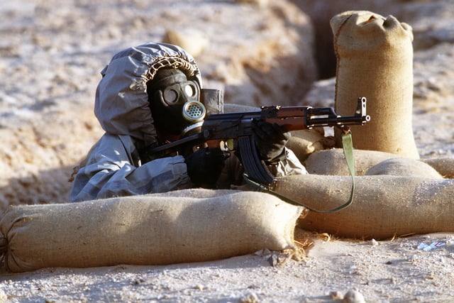 During a firepower demonstration activity, a Syrian soldier wearing a Soviet-made Model ShMS nuclear-biological-chemical warfare mask aiming a Chinese Type-56 automatic assault rifle