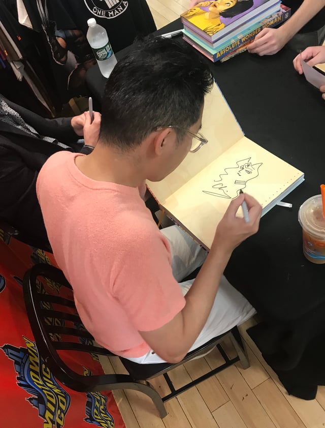 Cliff Chiang, who drew the New 52 version of the Wonder Woman series, sketching a character in a fan's copy of one of the Absolute editions collecting his work on it, at a signing at Midtown Comics in Manhattan