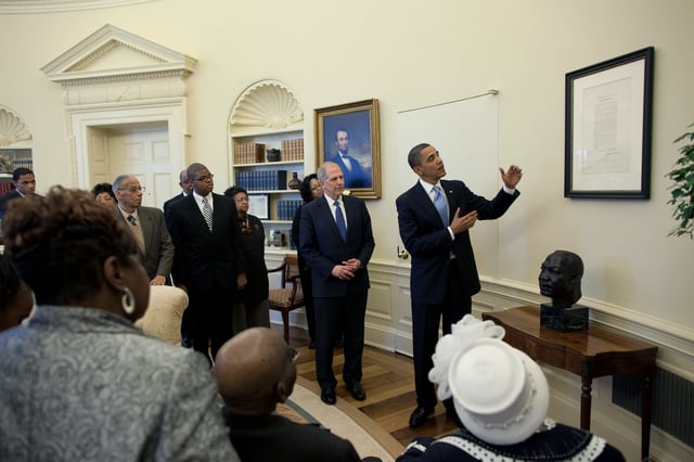 President Barack Obama views the Emancipation Proclamation in the Oval Office next to a bust of Martin Luther King, Jr.
