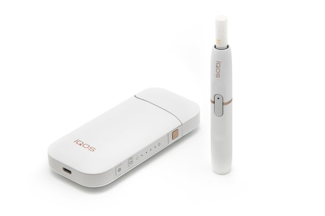 Philip Morris International's IQOS device with charger and tobacco stick.