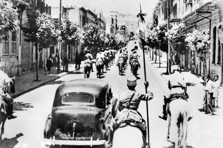 The fall of Damascus to the Allies, late June 1941. A car carrying Free French commanders General Georges Catroux and General Paul Louis Le Gentilhomme enters the city, escorted by French Circassian cavalry (Gardes Tcherkess).