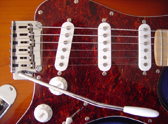 Detail of a Squier-made Fender Stratocaster. Note the vibrato arm, the 3 single-coil pickups, the volume and tone knobs.