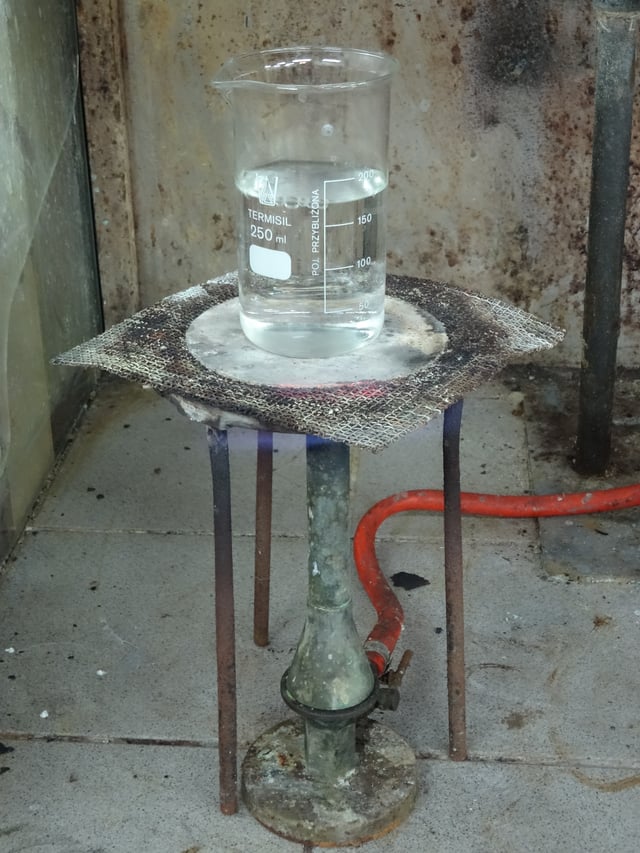 A laboratory heat spreader made of asbestos, on tripod over a Teclu burner.