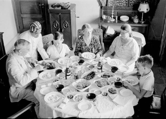 Dutch family enjoying a large Rijsttafel dinner, 1936.