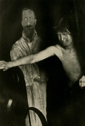 The fraud medium Eva Carrière in a séance with cardboard cut out figure of King Ferdinand of Bulgaria.