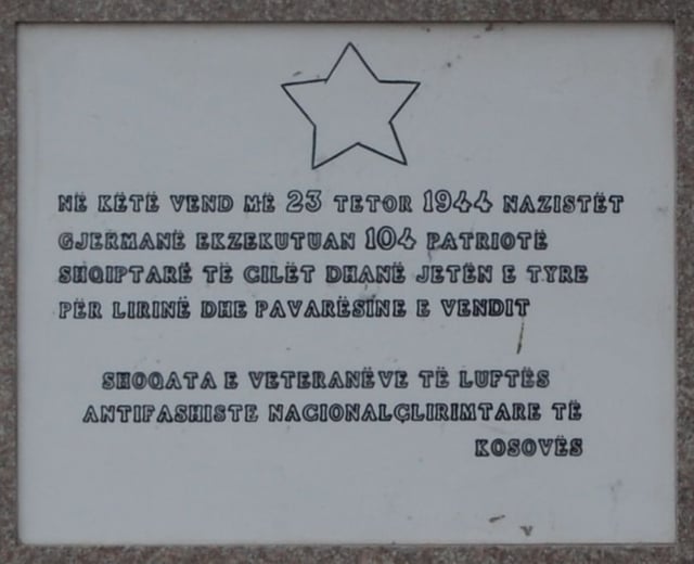 Plaque on a war memorial in Pristina. The text reads At this location on October 23, 1944, German Nazis executed 104 Albanian patriots who gave their lives for the freedom and independence of their country - Society of anti-Nazi and national liberation veterans of Kosovo.