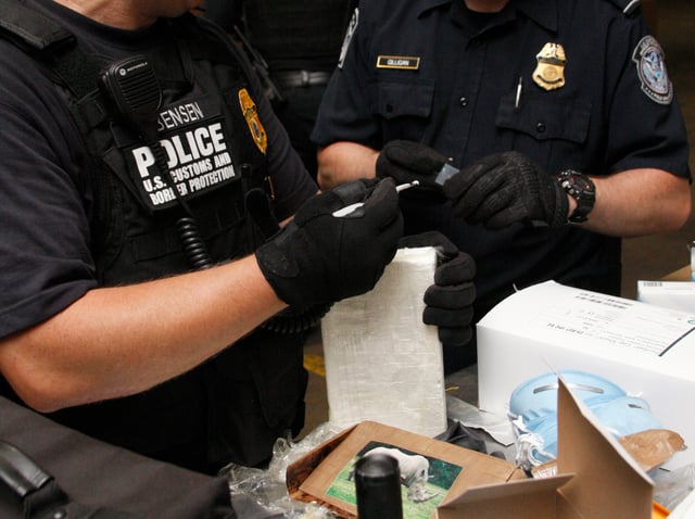 United States CBP police inspect a seized shipment of cocaine