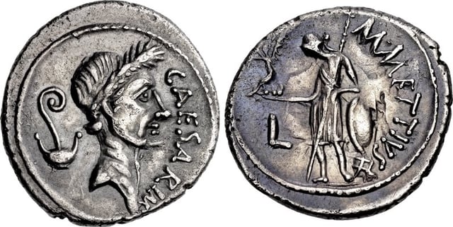 Denarius of Caesar, minted just before his murder, in 44 BC. It was the first Roman coin bearing the portrait of a living person. The lituus and culullus depicted behind his head refer to his augurate and pontificate. The reverse with Venus alludes to his claimed descent from the goddess.